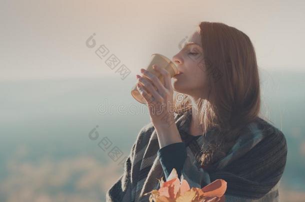 年幼的女人和关闭着的眼睛喝饮料从纸杯子.花束关于