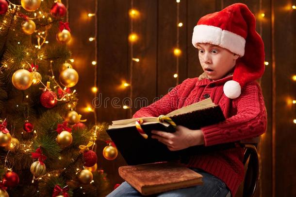 青少年男孩阅读书,一次室内的在近处装饰圣诞节树wickets三柱门