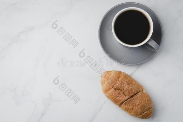 咖啡豆破.灰色的杯子和黑的咖啡豆和羊角面包向白色的