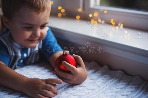 幸福的<strong>小孩</strong>男孩佃户租种的土地红色的圣诞节球在近处窗室内的winter<strong>冬天</strong>