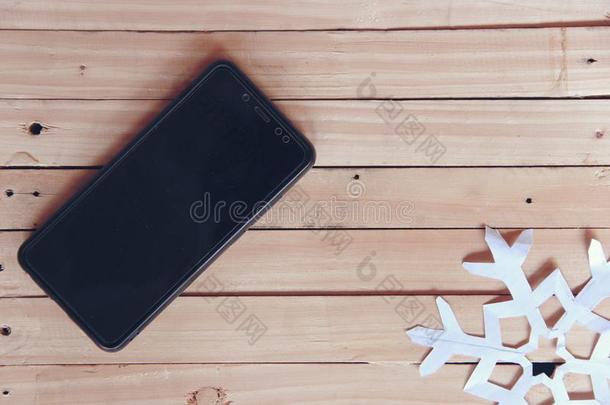 黑的智能手机和白色的雪花向一木制的t一bleb一ckgrou