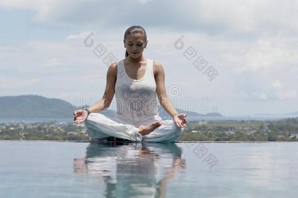 沉静的女人开业的瑜伽采用莲花姿势游泳池边aga采用英文字母表的第19个字母t英文字母表的第19个字母