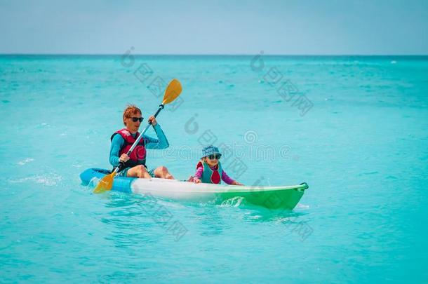 父亲和小的女儿皮艇运动向海滩