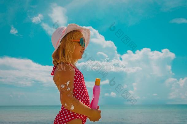 太阳保护观念-小的女孩和防晒霜在海滩