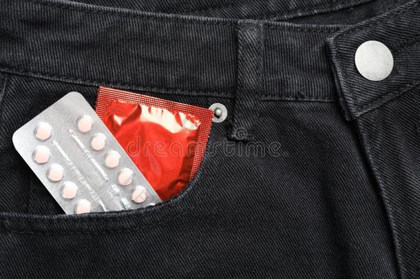 特写镜头看法关于牛仔裤和红色的避孕套和出生控制药丸.英文字母表的第19个字母