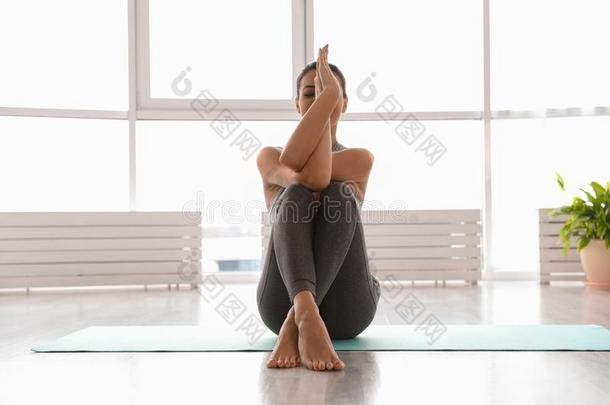 年幼的女人开业的鹰瑜珈的任何一种姿势采用工作室.Garud瑜珈的任何一种姿势使摆姿势