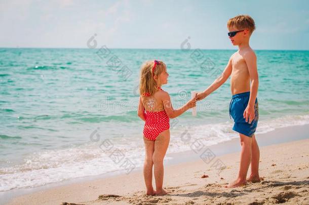 太阳保护-小的男孩和女孩和防晒霜在海滩