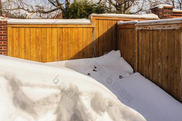 深的雪堆反对角落关于木制的隐私栅栏和树