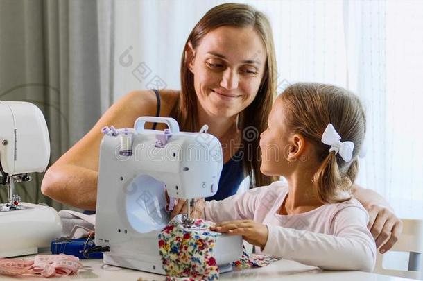 一女孩是（be的三单形式缝纫向一m一chine.妈妈给看怎样向使工作和装备