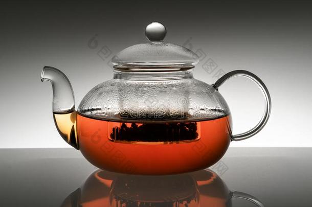玻璃茶壶和热的茶水向灰色梯度背景和反射的
