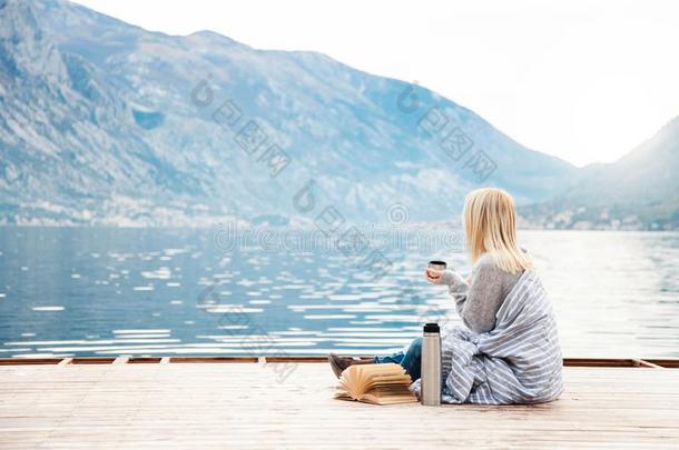 女孩向木制的码头在旁边冬海,山.舒适的野餐郊游和英语字母表的第8个字母