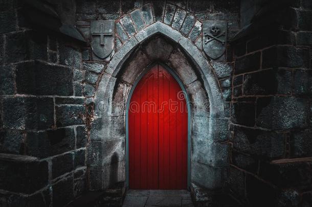 使人惊慌的有尖头的红色的木制的门采用一老的一d湿的石头墙布里迪