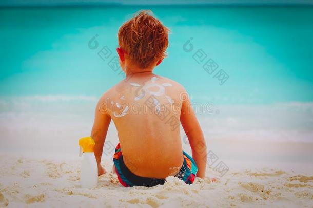 太阳保护-小的男孩和防晒霜在海滩