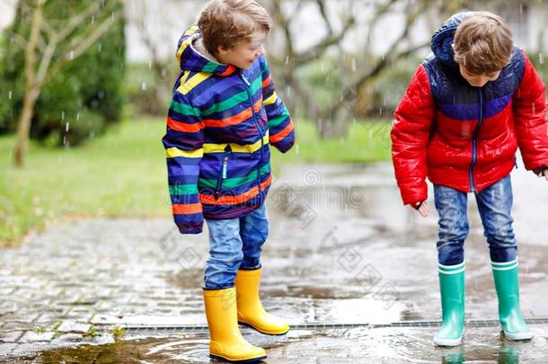 两个小的小孩男孩向道路向学校步行在的时候雨夹雪或雹,雨