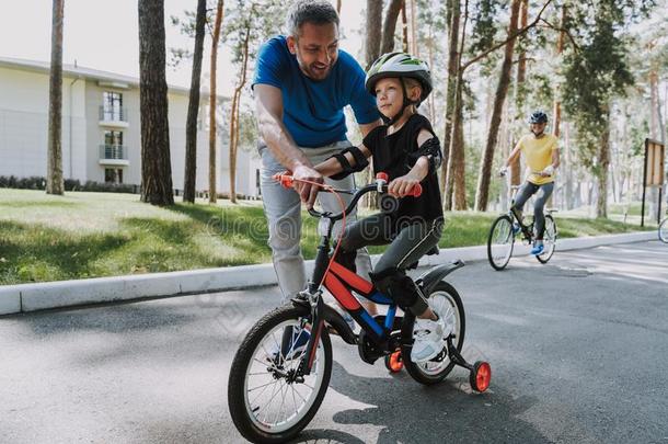 快乐的父亲教学他的女儿向乘一自行车