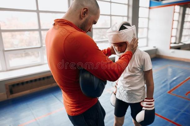 教练的一份小的男孩放向拳击齿轮采用健身房