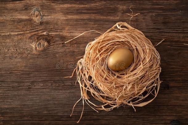 唯一的和<strong>贵</strong>重的<strong>金色</strong>的鸡蛋和窝向木制的背景.