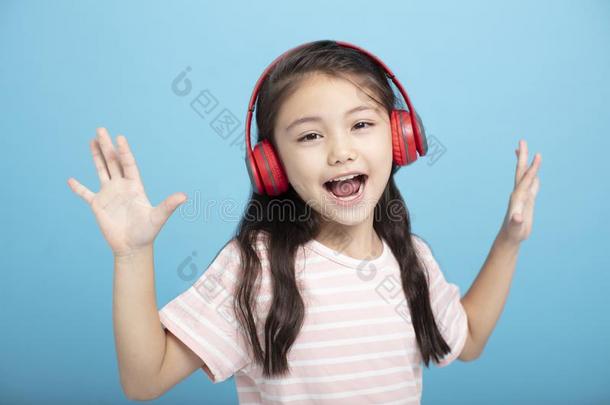 幸福的小的女孩和耳机收听的和唱歌歌曲