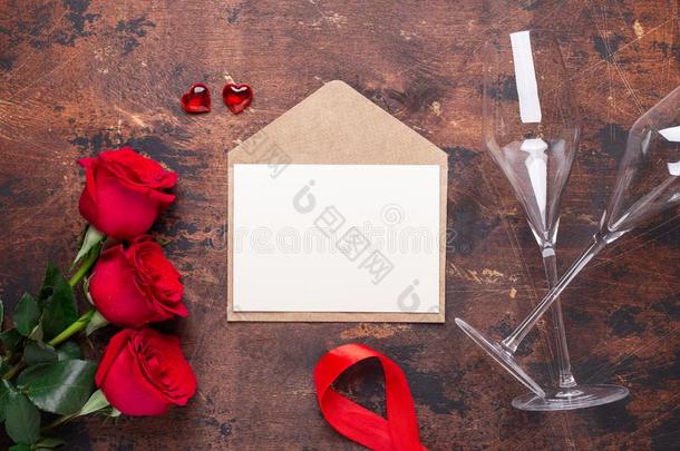 红色的玫瑰花花束,信封和香槟酒眼镜向木材