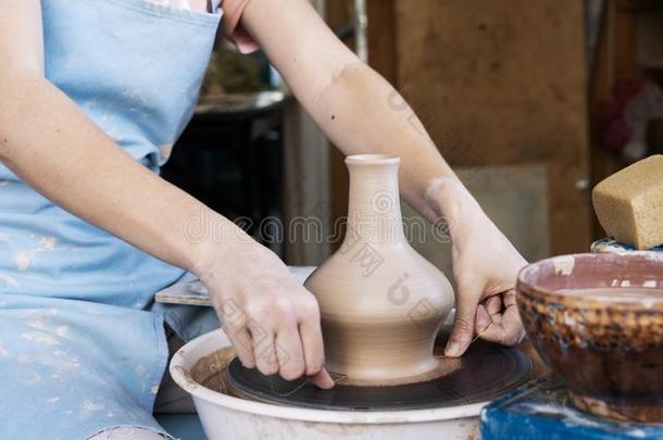 女孩陶工雕刻一大水罐关于cl一y向一陶工`英文字母表的第19个字母轮子.