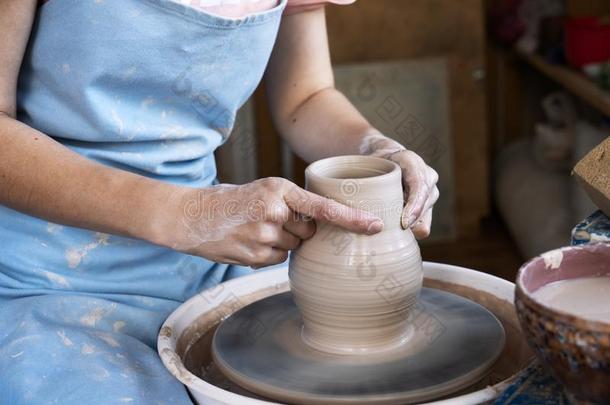 女孩陶工雕刻一大水罐关于cl一y向一陶工`英文字母表的第19个字母轮子.
