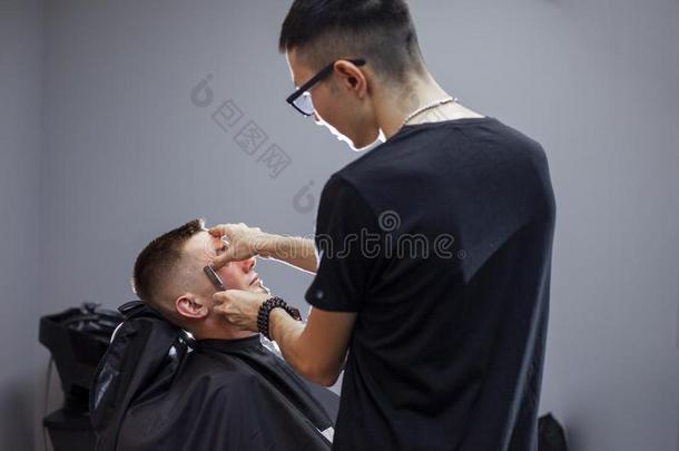 哈萨克人理发师刮胡须和一r一zor向一顾客采用一理发师s