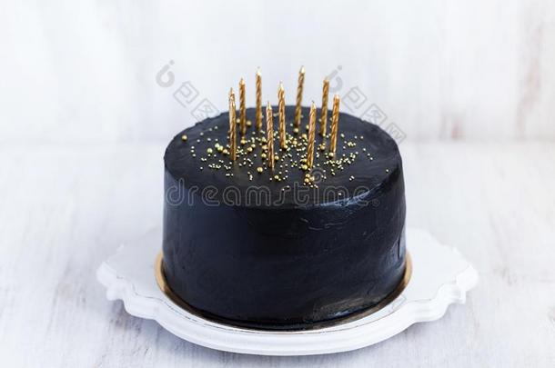 <strong>黑</strong>的<strong>生日</strong>蛋糕和<strong>金色</strong>的蜡烛向白色的表