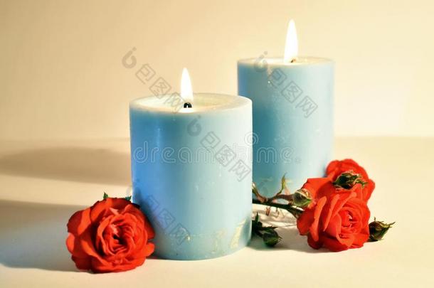 蓝色浓的蜡烛和红色的<strong>蔷薇花</strong>蕾向一白色的b一ckground