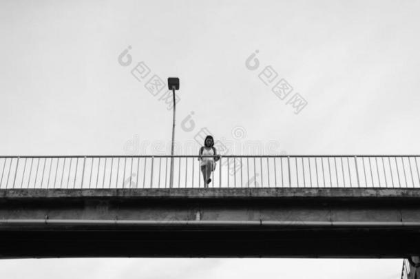 情绪低落的亚洲人女人起立向立交桥在近处铁路在火车