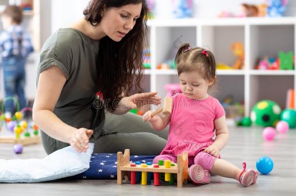 漂亮的女人和小孩演奏教育的玩具在幼儿园或英语字母表中的第四个字母