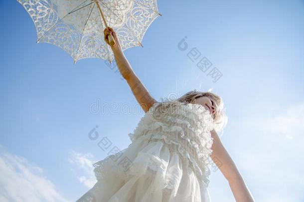美丽的亚麻色的女孩使摆姿势和白色的遮阳伞雨伞