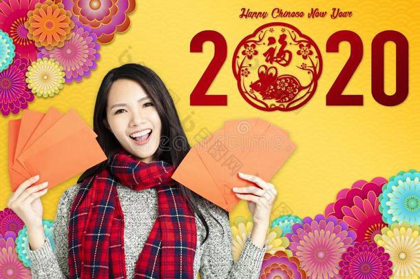 亚洲人女人展映红色的信封为中国人新的年.中国人英语字母表的第20个字母