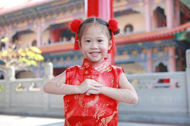 幸福的小的亚洲人小孩女孩使人疲乏的红色的旗袍和打招呼