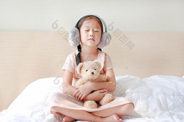 值得崇拜的小的亚洲人小孩女孩使人疲乏的冬护耳和热烈地拥抱