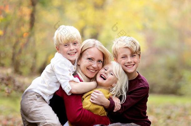幸福的年幼的母亲热烈地拥抱她漂亮的,微笑的小的孩子们