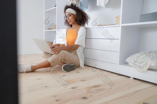 快乐的非洲式发型美国人女人工作的向便携式电脑在家
