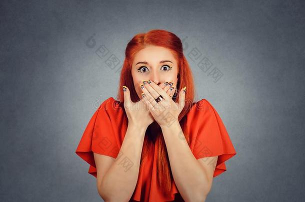 红发的人女孩掩蔽物口和手和目不转睛的在照相机