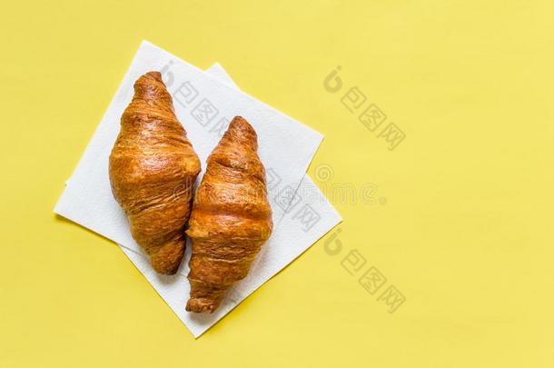 早餐糕点两个羊角面包向黄色的背景