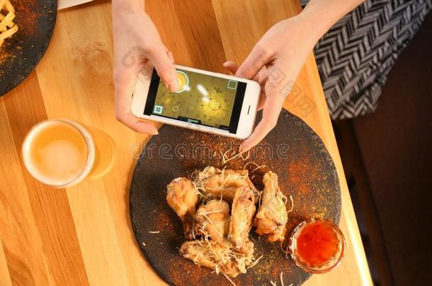 女人演奏游戏使用智能手机在表和barbecue吃烤烧肉的野餐飞行章,顶