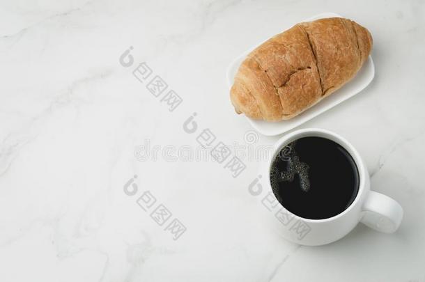 白色的马克杯和黑的咖啡豆和羊角面包向白色的st向e表.