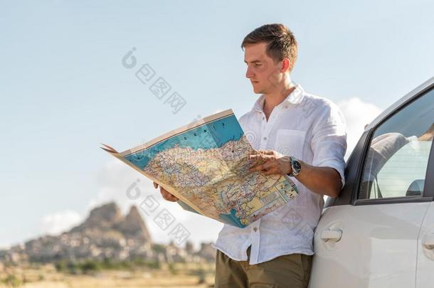 年幼的男人起立在旁边指已提到的人汽车有样子的在纸地图