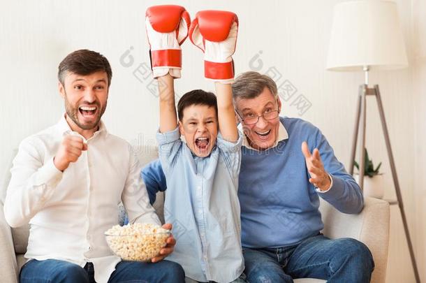 男孩,父亲和祖父观察拳击比赛向television电视机室内的