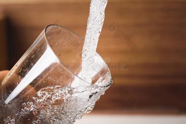 装满玻璃关于水从不锈的钢厨房水龙头.德林河