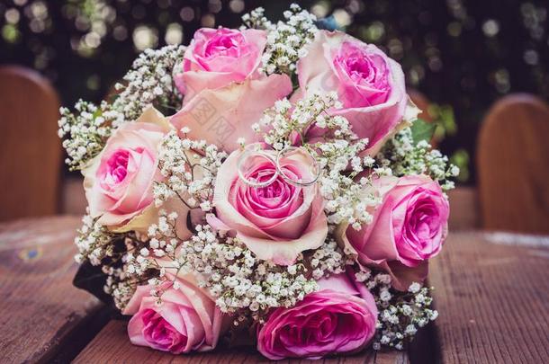 婚礼花束和粉红色的玫瑰向木制的表和戒指