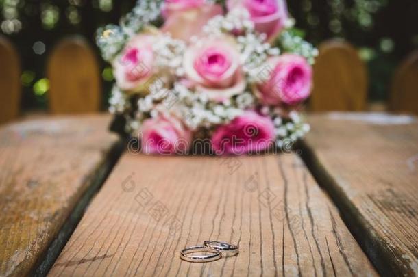 婚礼花束和粉红色的玫瑰向木制的表和戒指