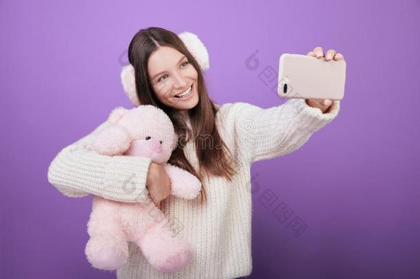 女孩紧抱一玩具一ndt一kes一自拍照向一紫色的b一ckground