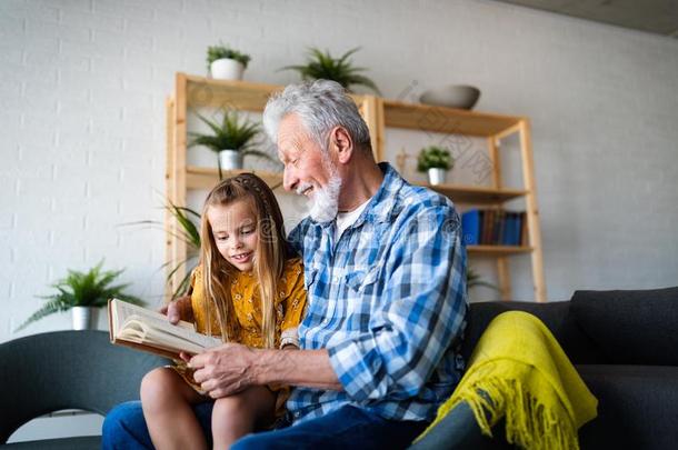 幸福的小的女孩和祖父阅读故事书在家