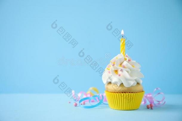美味的生日纸杯蛋糕和蜡烛向蓝色背景.空间