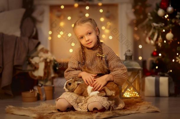 幸福的小的女孩和棕色的兔子在圣诞节前夕