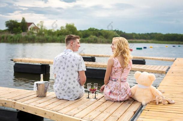 浪漫的日期使惊奇.一年幼的家伙和一女孩向一木制的码头.